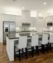 Modern kitchen with white cabinetry, stainless steel appliances, and a central island with four black and white bar stools